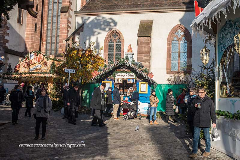 Imagen, una calle durante el día, con los puestos de navidad y gente alrededor.