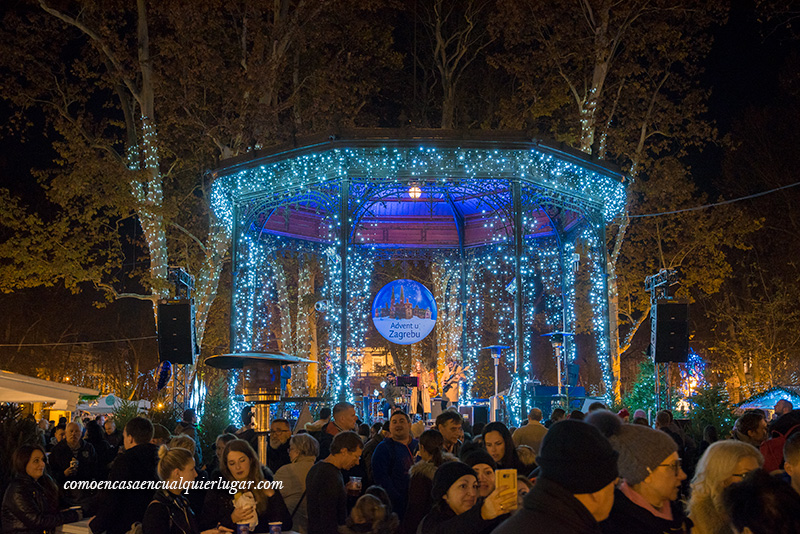 Croacia en Navidad. Imagen nocturna de un quiosco de música con iluminación azul. Al ser tan grande se ve una multitud de gente pasando por sus alrededores.