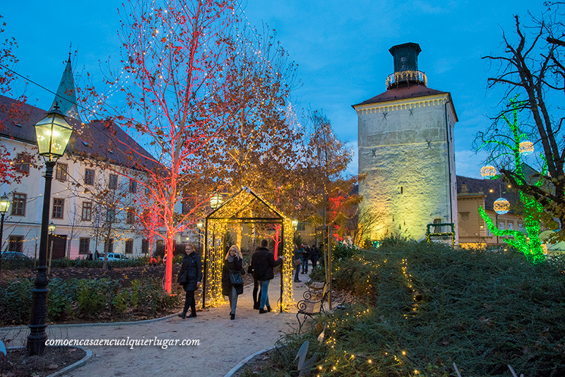 Plaza Strossmayer Zagreb. Imagen, una plaza con iluminada con diferentes colores, rojo ,a amarillo y verde.