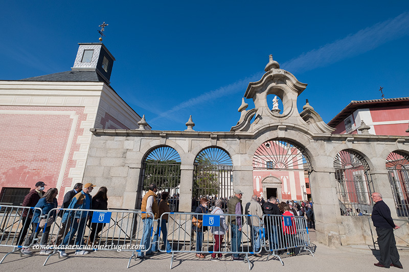 Imagen, entrada al santuario. La gente hace cola para entrar y recoger el pan con queso. Hay unas vallas as puestas provisionalmente para ordenar el aforo.fiestas Fuencarral pan y queso