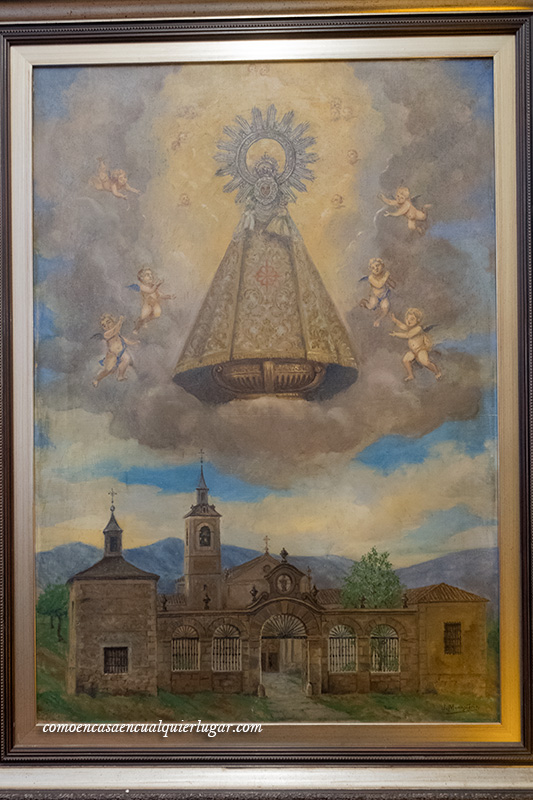 Imagen, un cuadro antiguo en el que se ve a la virgen de valverde rodeada de angelitos entre nubes y debajo  todo el santuario.