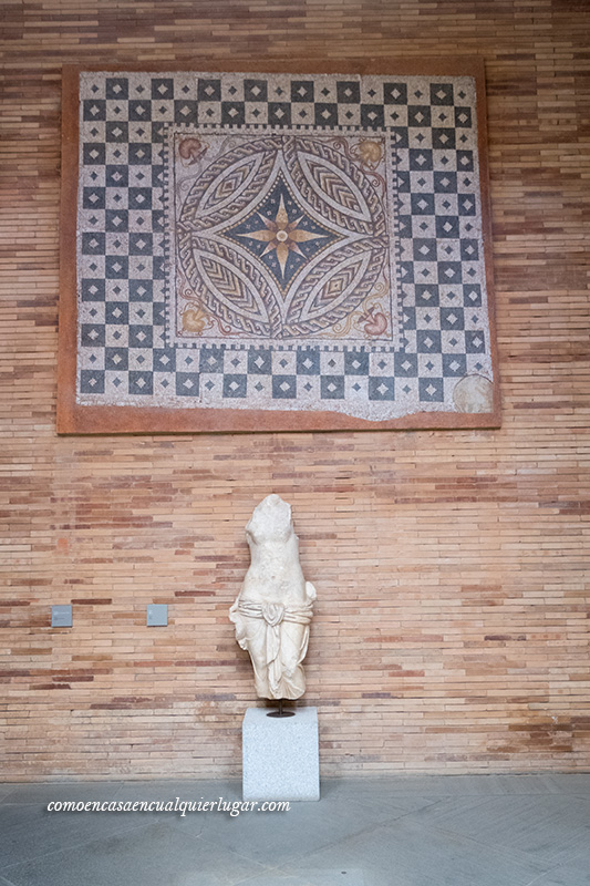 foto con Pared en la que hay un mosaico y una escultura sin brazos ni piernas  en el Museo Nacional de Arte Romano Mérida
