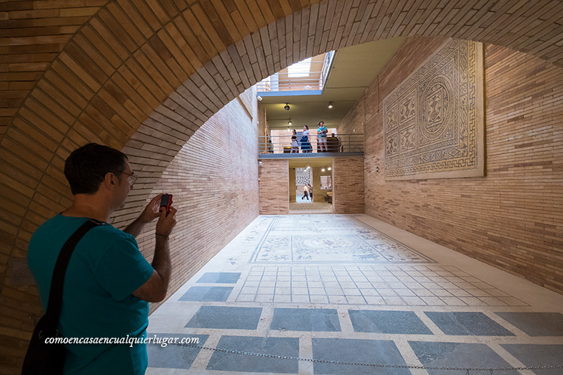 imagen, un hombre hace una foto a los mosaicos en una sala con un arco superior y muy profunda, que visitar en Mérida