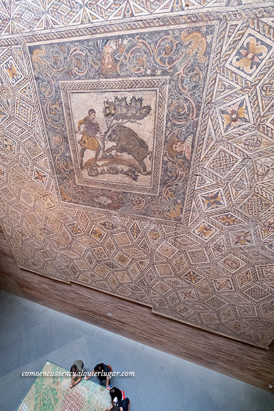 fotografía, a tamaño real de un mosaico romano, siendo inmensa, vista desde arriba hacia abajo y dado su gran tamaño se ven personas pequeñas por la perspectiva.