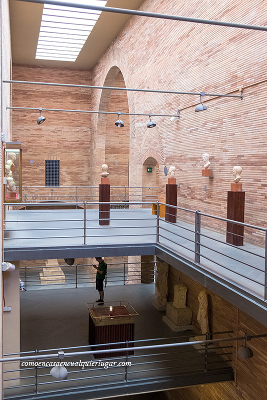 Foto en vertical en la que se ven diferentes plantas-pisos de las exposiciones, con bustos romanos y la silueta de una persona Museo Nacional de Arte Romano Mérida